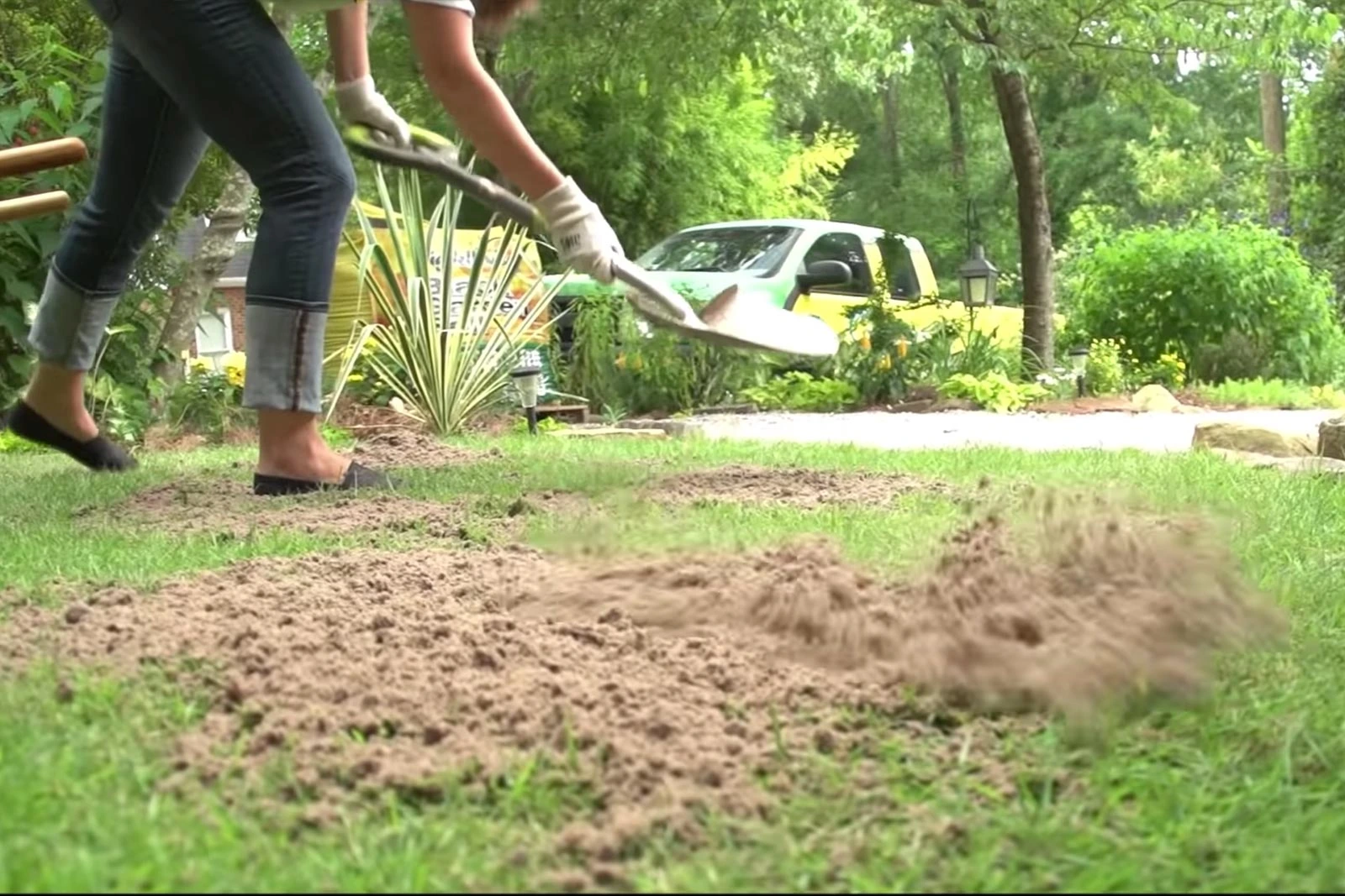 Tuinier brengt topdressing aan op een gazon om het gras te egaliseren en te verbeteren.